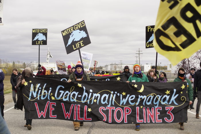 Protesters holding banner that reads We will stop Line 3