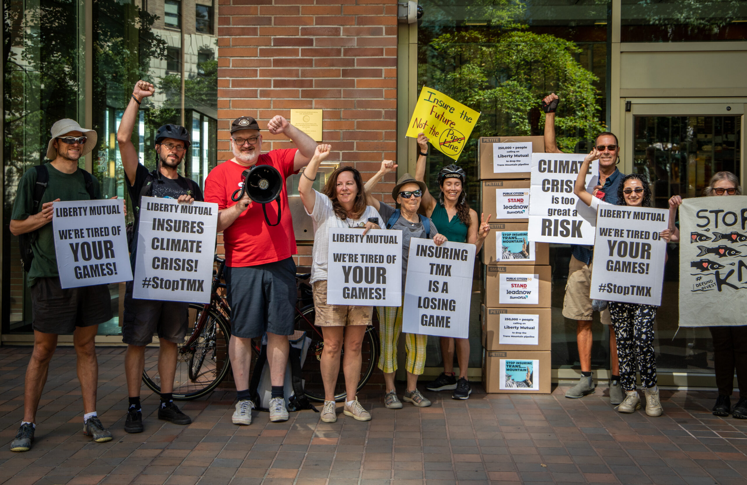 group of people standing in front of liberty mutual office in vancouver holding signs