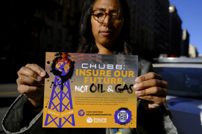 A person holding a yellow and purple flyer detailing Chubb atrocities that was handed out to passerbys at the protest.