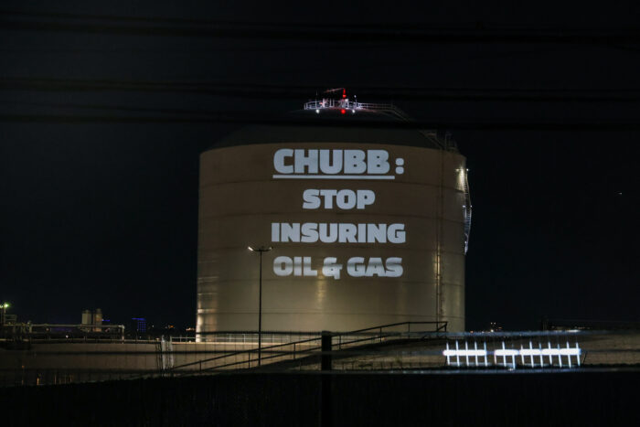 Photo is of a light projection on Brooklyn methane gas tank which reads "Chubb: Stop Insuring Oil and Gas"