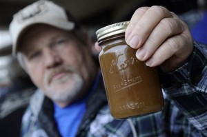Jimmy Murphy of Sprigg, W.Va., holds a jar filled with well water from his home. (AP Photo/Jeff Gentner)