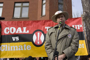 photo of a man speaking in front of a banner which reads in part: coal vs. climate !